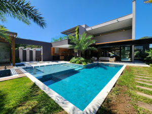 Casa de alto padrão com piscina, área gourmet integrada e jardim tropical em ambiente externo na Riviera de São Lourenço.