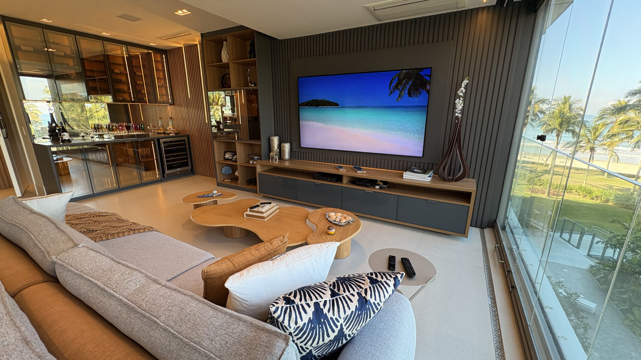 Sala de estar sofisticada com vista para o mar integra área de convivência e espaço gourmet em residência de alto padrão.
